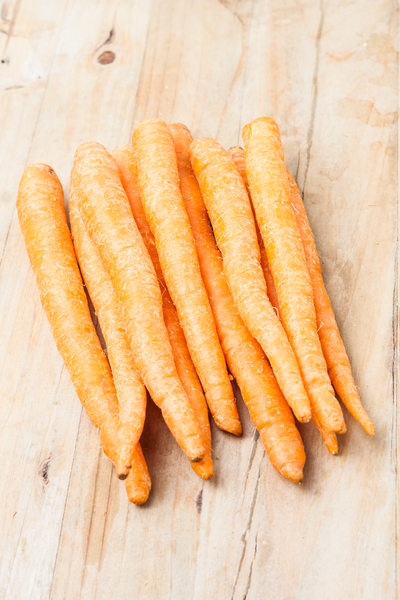 a bunch of fresh picked carrots on wooden background