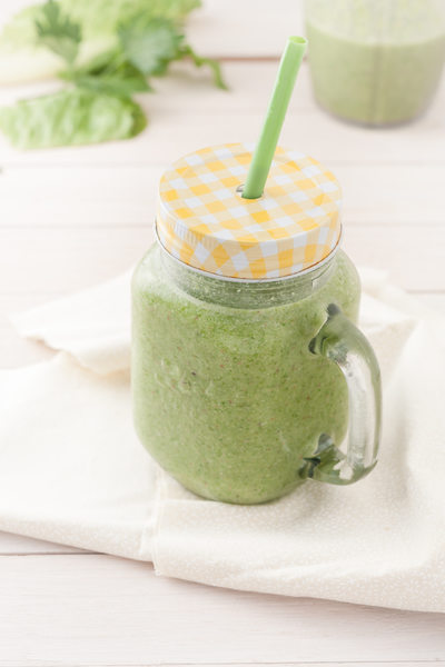 green smoothie in a glass jar with lid and a straw