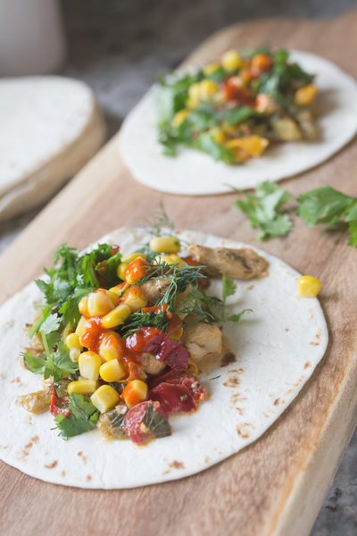 fresh tacos with chicken, vegetables and herbs on a wooden board
