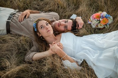 Couple lying in a field in a country-style wedding.