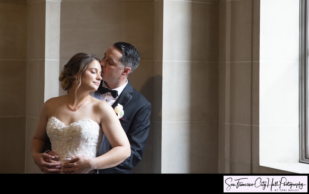 South facing window light softly colors bride and groom kiss at city hall