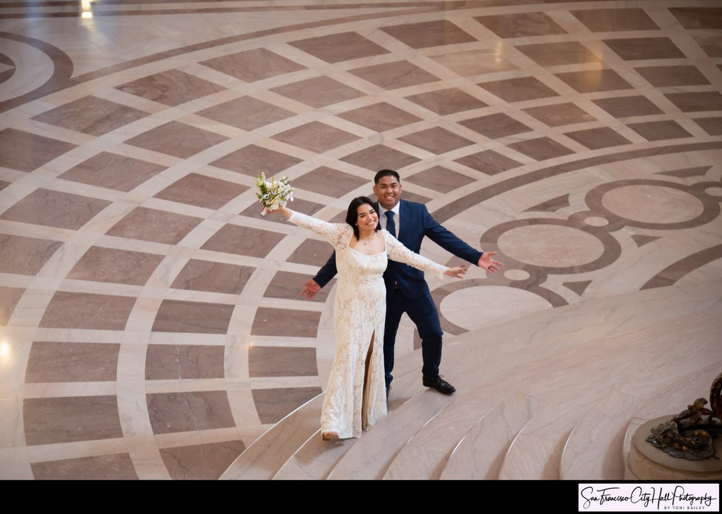 Newlyweds celebrating at the Base of SF City Hall's Grand Staircase