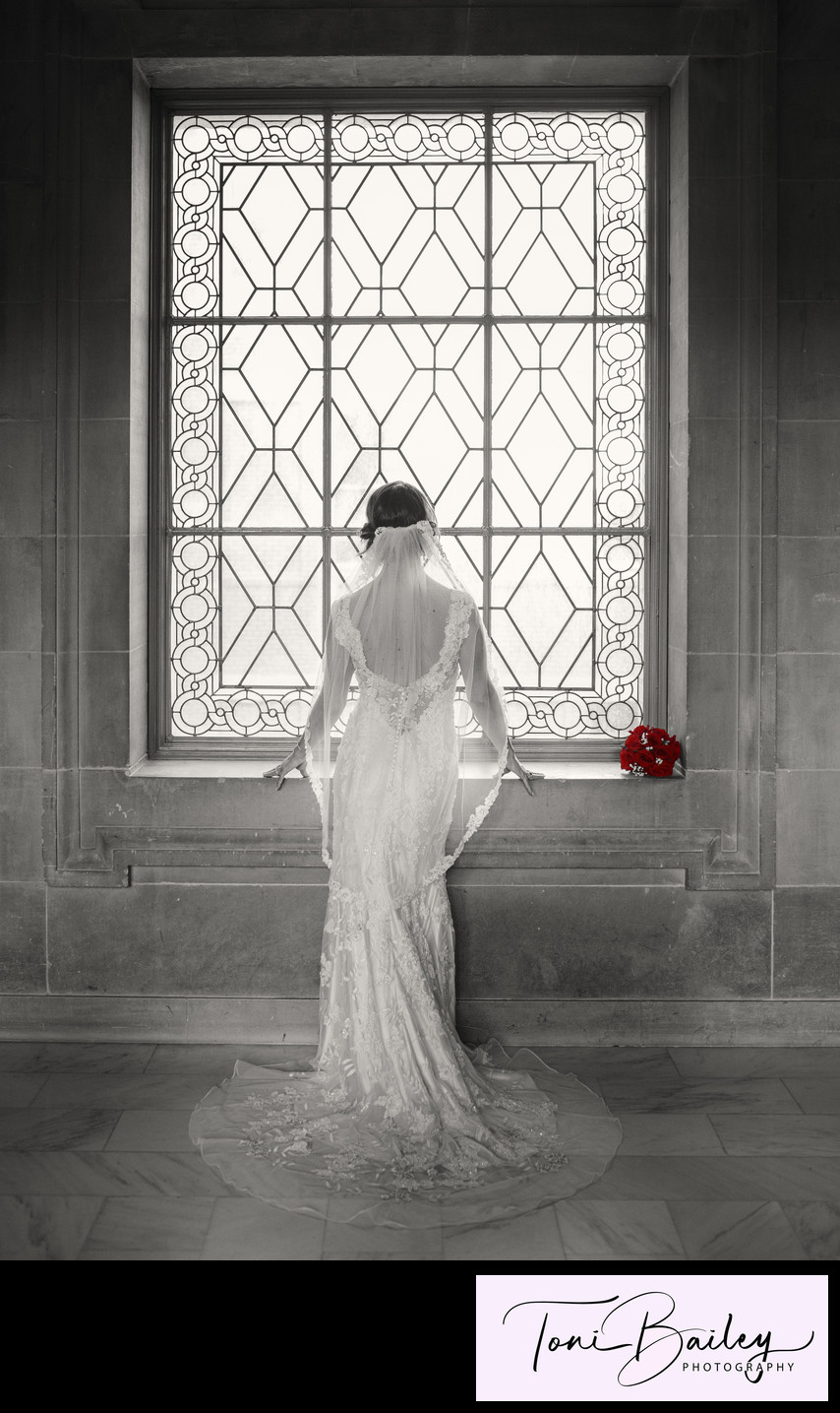 Bride with red roses in window