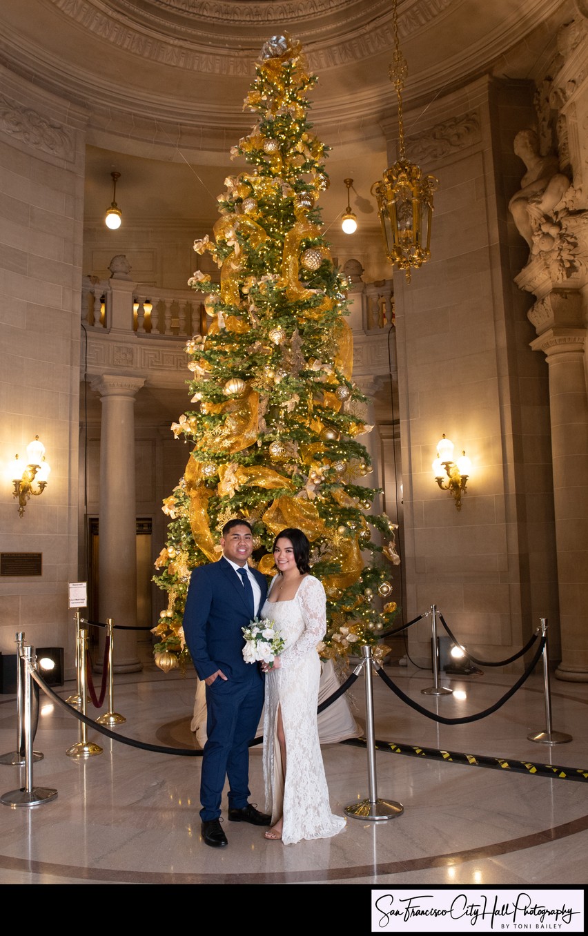 Bride and Groom pose in front of Christmas tree at SF City Hall