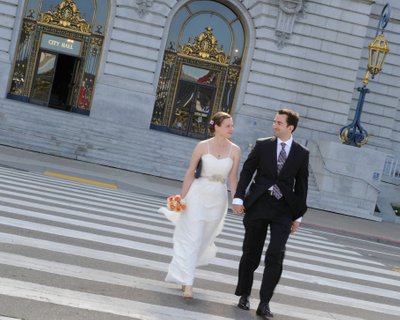 Happy newly married couple walk across the street in front of SF City Hall