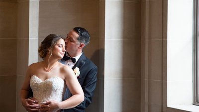 South facing window light softly colors bride and groom kiss at city hall