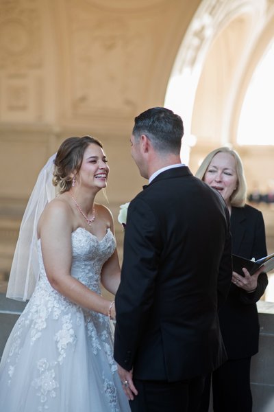 Bride, groom and Wedding officiant share a laugh during ceremony