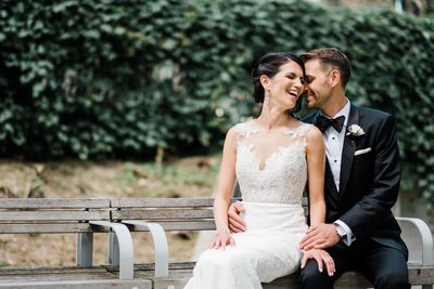 Bride and Groom Sit on a Bench at Storys Building Wedding