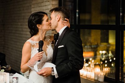 Bride and Groom Kiss During Speech at Storys Building Wedding