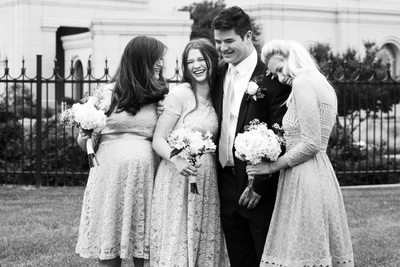 Candid photo of groom laughing with sisters
