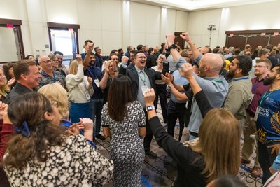 Crowd of people cheering at a perseus group conference