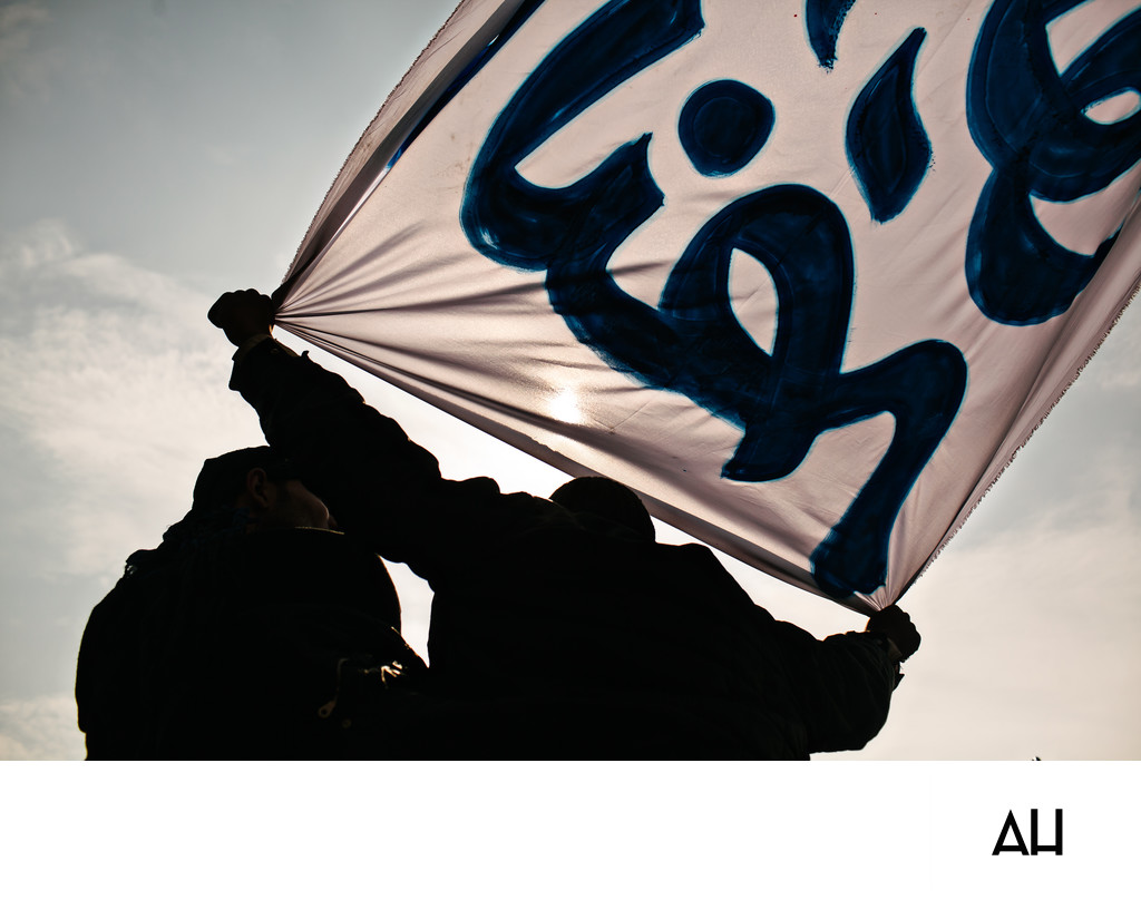 Silhouetted Protesters Hold Arabic Banner