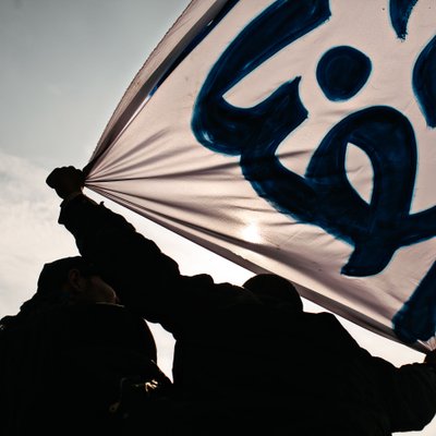 Silhouetted Protesters Hold Arabic Banner