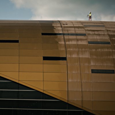 Worker Pressure-Washing a Modern Building Facade