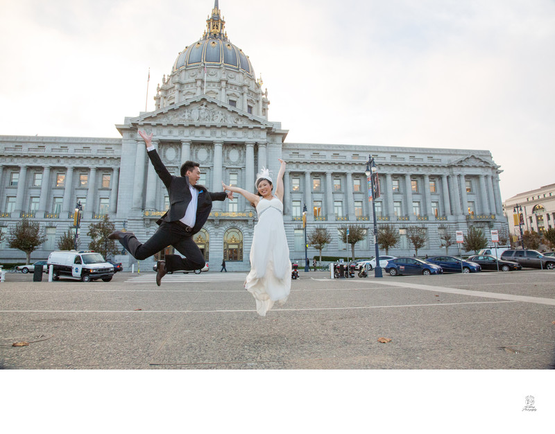 A couple, jumping for joy after their wedding at City Hall