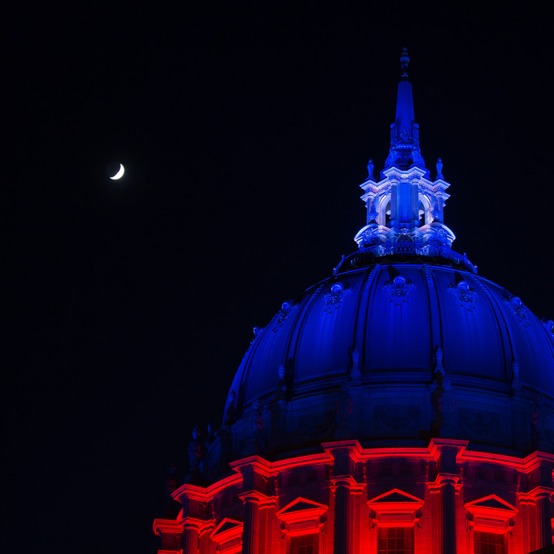 crescent moon over an illuminated City Hall