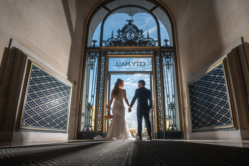 Couple exiting SF CIty Hall with beautiful sky