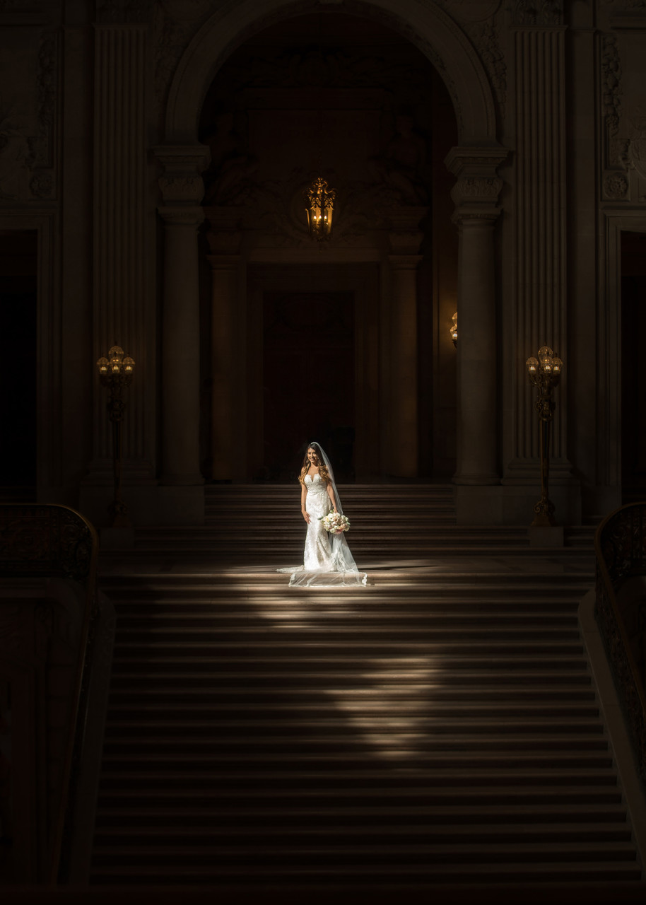 A bride poses in natural light coming down from the fourth floor window