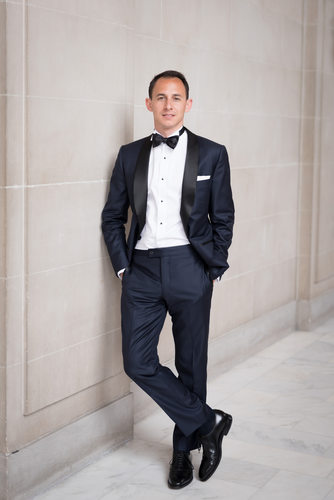 groom poised confidently, dressed in a sleek black tuxedo