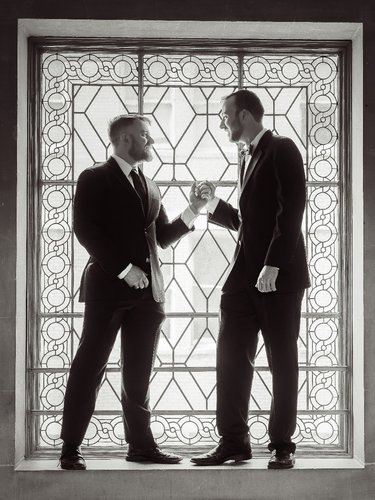 gay couple in window light two grooms in window light