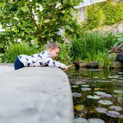 cute kid dropping coin into fountain at wedding