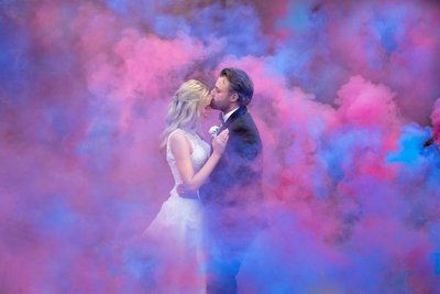 Bride and groom with pink and blue smoke bomb background