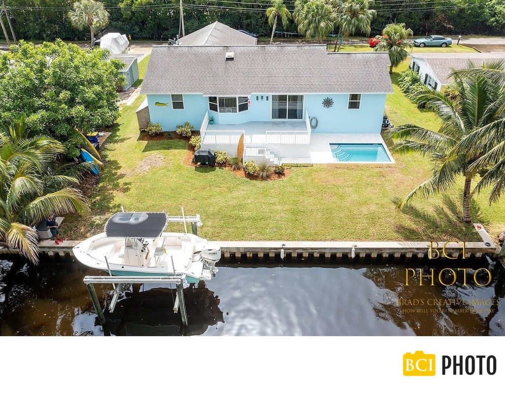 Waterfront pool home photograph with a boat on a lift