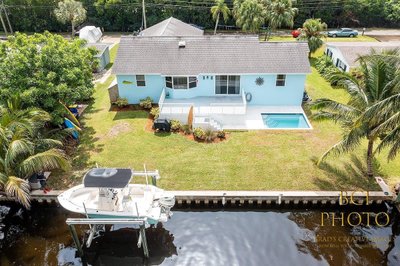 Waterfront pool home photograph with a boat on a lift