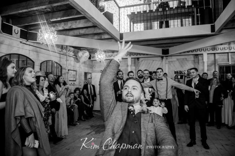 Groom Throwing Garter at Barn Weddings
