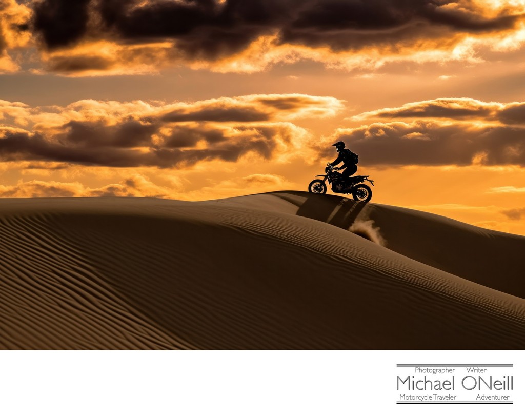A Lone Motorcyclist Climbing The Dunes At Sunset In Southern California
