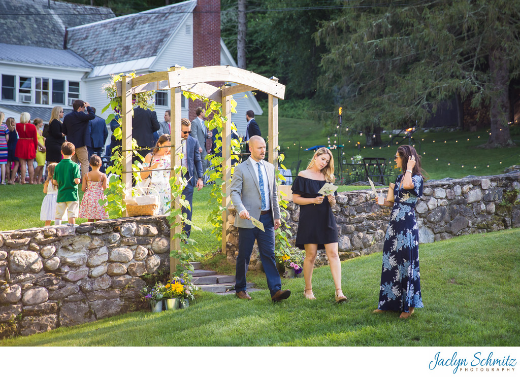 Wedding guests walk through arbor to ceremony