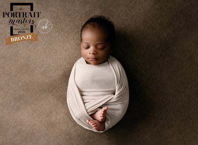 Baby wrapped in cream with brown background