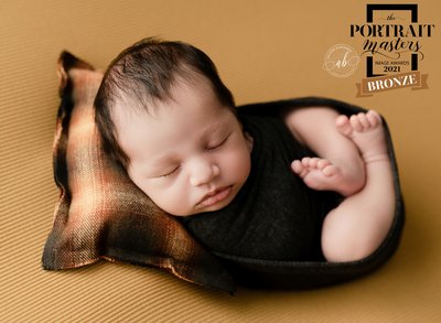 Baby wrapped in dark grey with yellow background