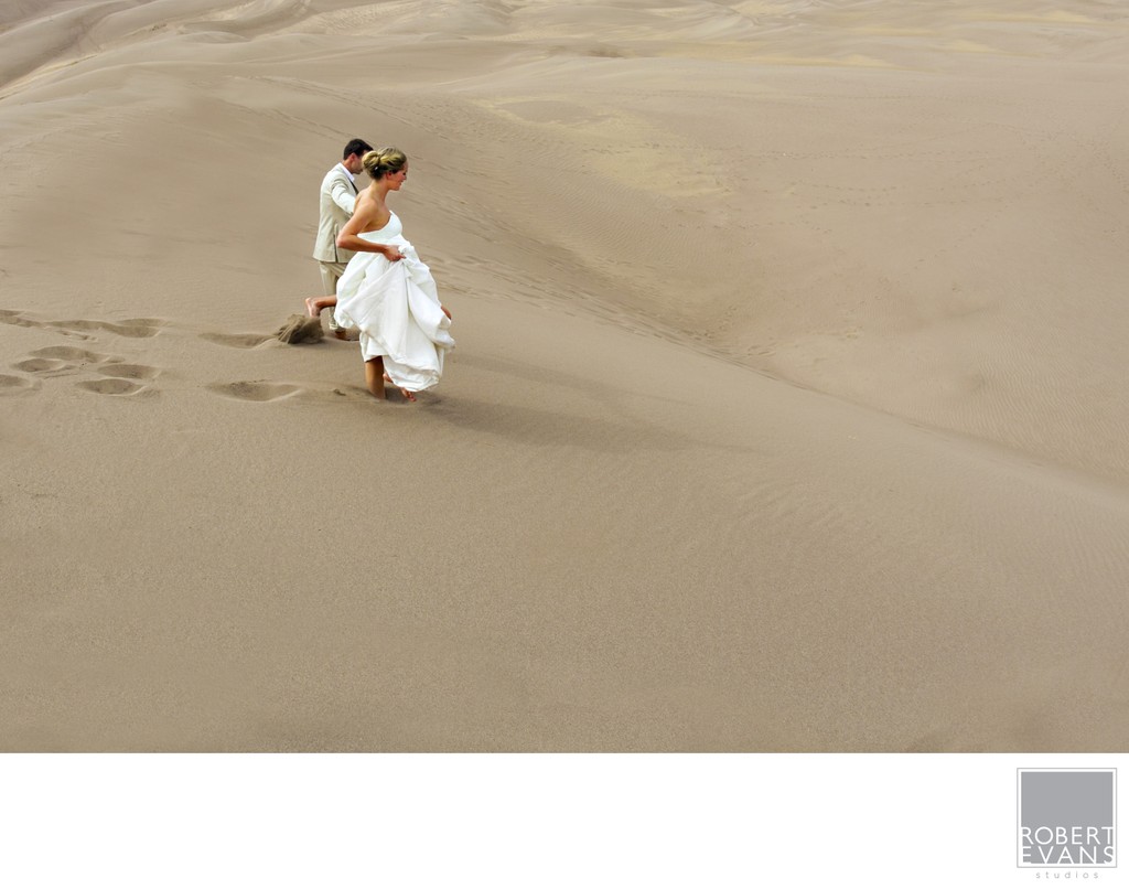 Bride & Groom run down a sand dune 