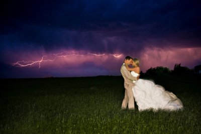 Bride & Groom Kiss as a bolt of lightning flashes in the sky.