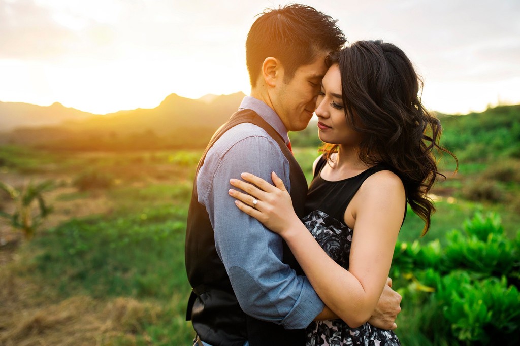 Couple embracing in front of a sunlit mountain.