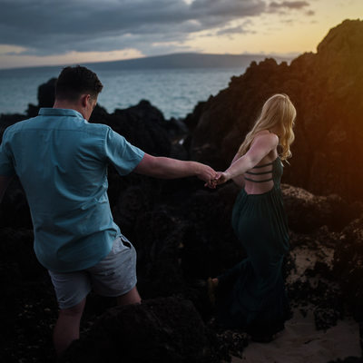 Couple climbing beach rocks in Maui, Hawaii