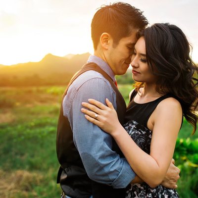 Couple embracing in front of a sunlit mountain.