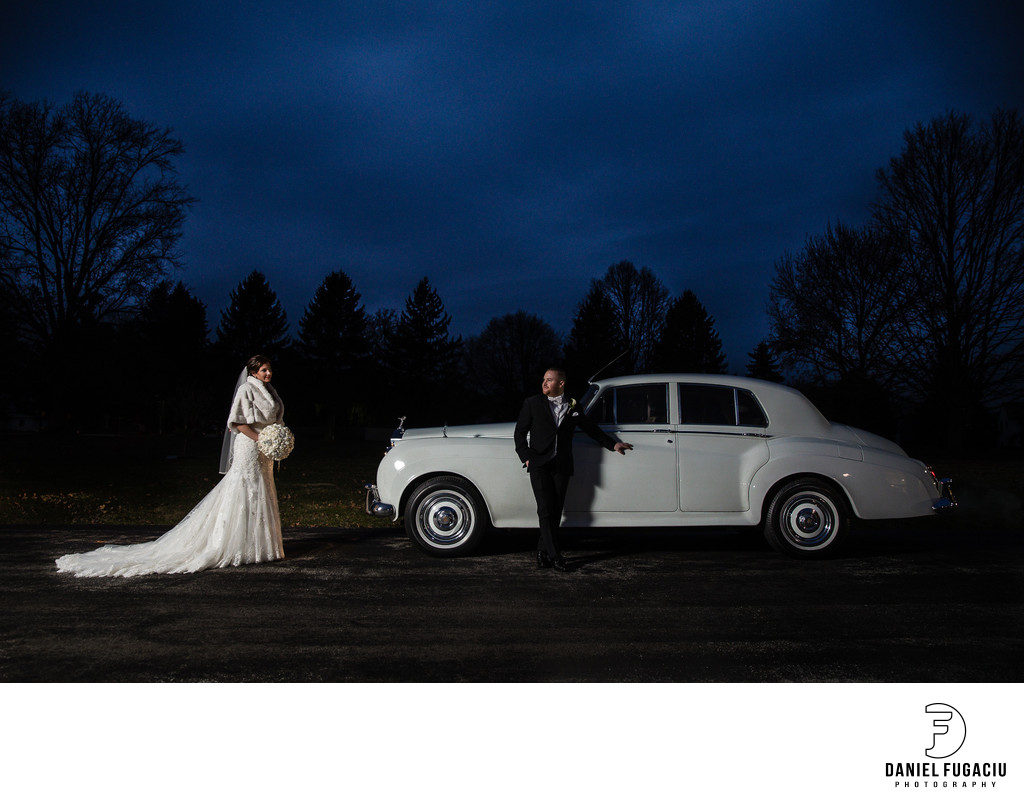 Bride and groom posing by Rolls Royce classic car