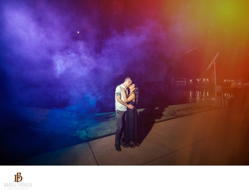 Engaged couple kissing in front of smoke bombs at sunset