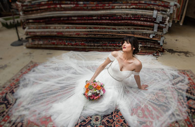 Bride holding bouquet posing on persian rug.