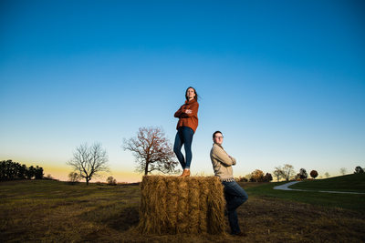 Engaged couple posing on a bale of hay