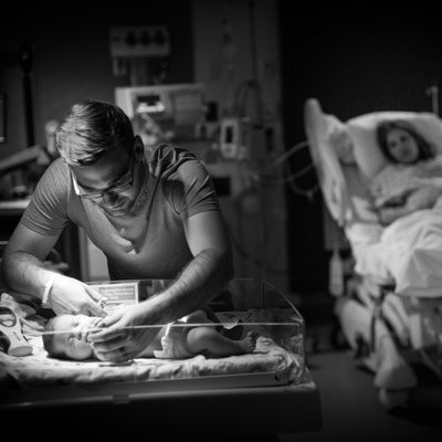 Darling View of Dad and Newborn Baby with Mom Watching