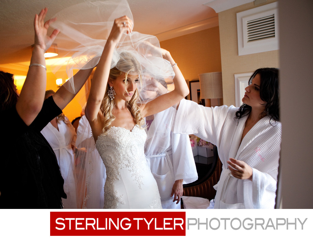 bride applying veil with bridesmaids