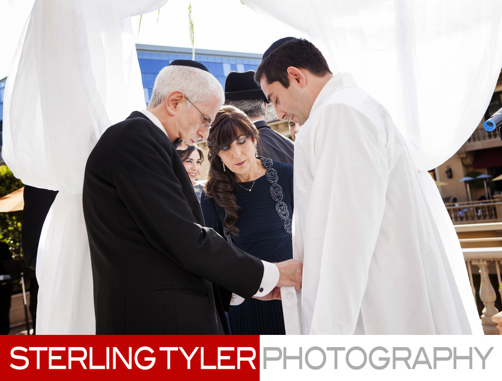 orthodox jewish groom puts on kittel during wedding
