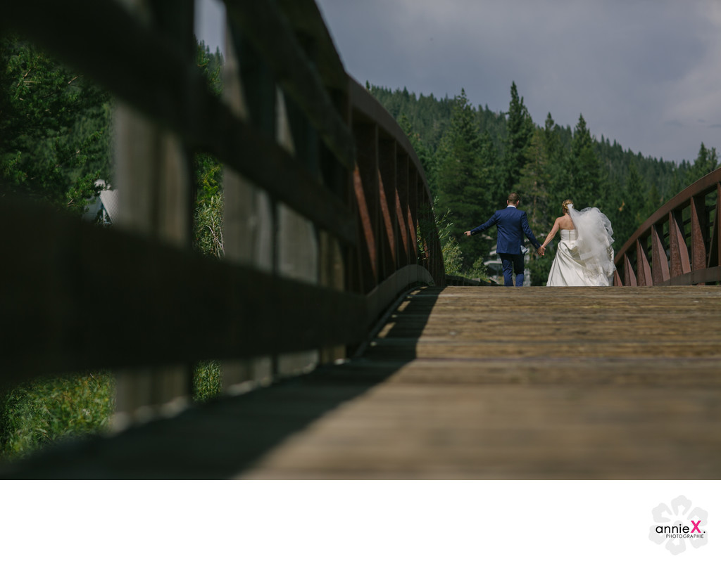 Bride and groom walking on footbridge in Squaw valley