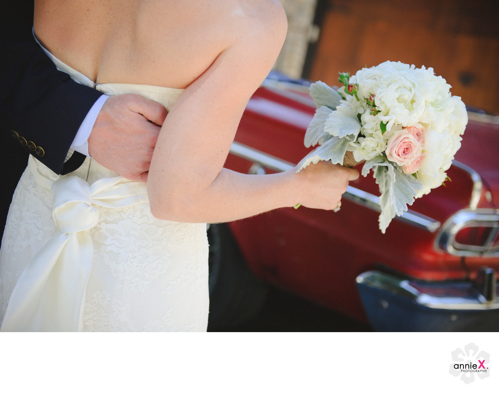 bride holding bouquet in front of red vintage car squaw