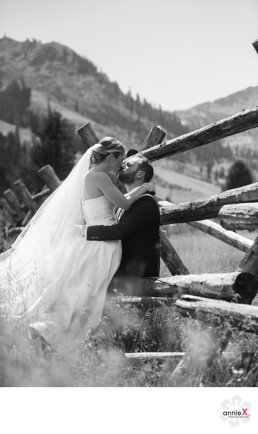 Newlyweds kissing leaning on wood fence in Squaw Valley