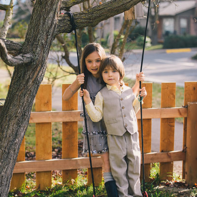 siblings boy and girl standing on swing