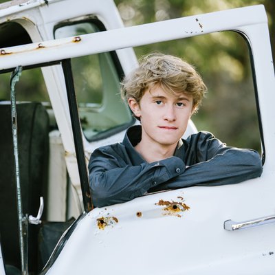 senior boy posing with old truck